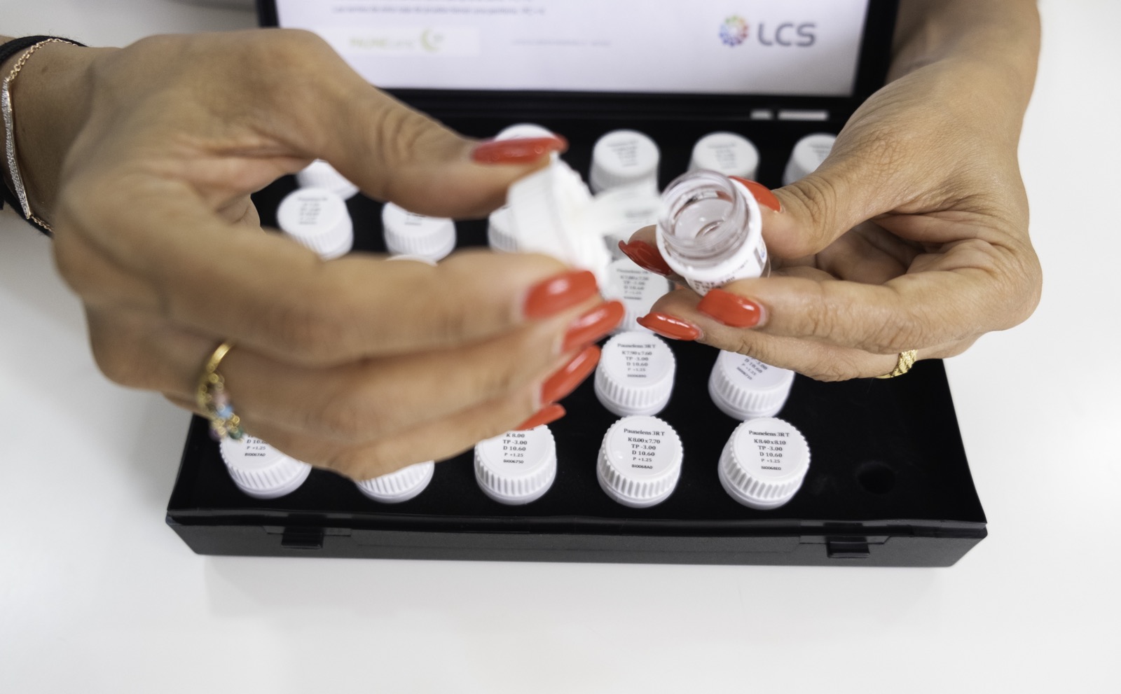 Optometrista manipulando un vial de la caja de lentes de contacto de prueba durante una adaptación